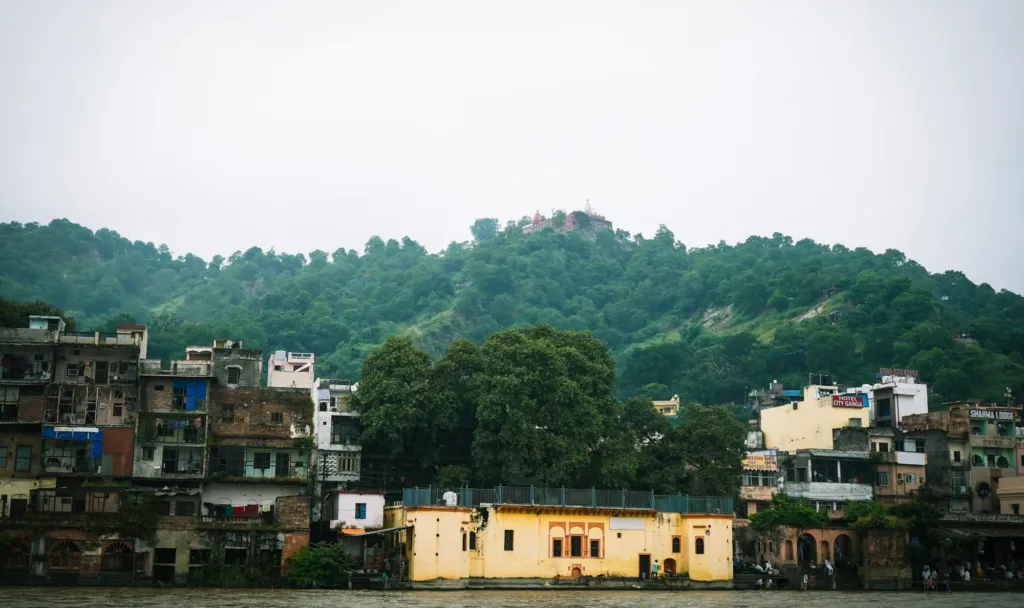 Ghats and riverside buildings of Har Ki Pauri with green hills behind, Haridwar (photo: Mustafa Fatemi, Unsplash)
